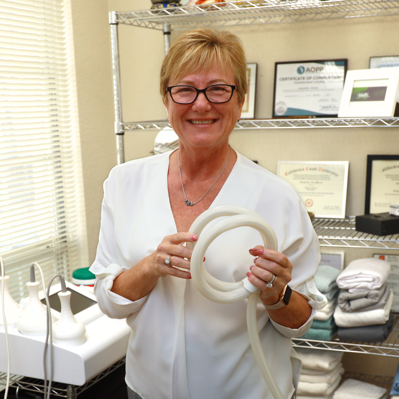 Jackie Messer at Balancing Self in Georgetown, TX, preparing PEMF equipment in her wellness therapy room surrounded by certifications and treatment tools.